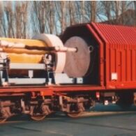 Transporteinrichtung (bestehend aus Lagergestell und Stoßdämpfern) mit Brennelementbehälter auf geöffnetem Eisenbahntransportwagon.